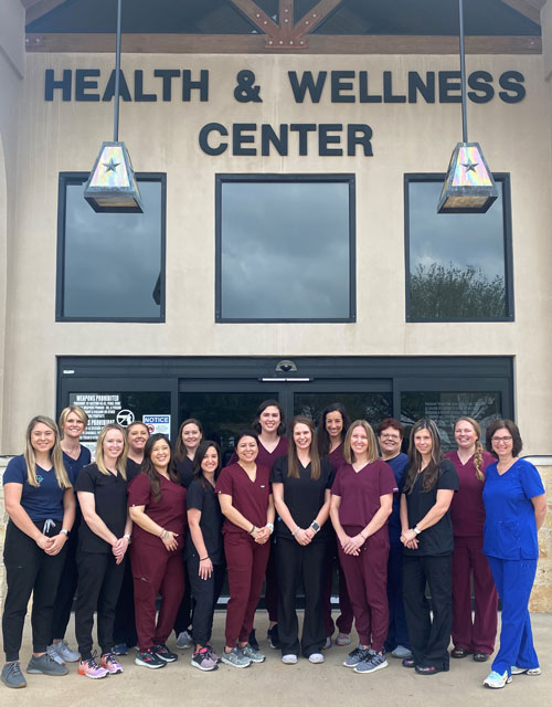 Picture of 8 female Therapy Dept staff members wearing scrubs. They are standing in front of the therapy dept.&apos;s pool inside