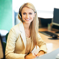 Picture of a woman wearing a headset while sitting at a desk smiling